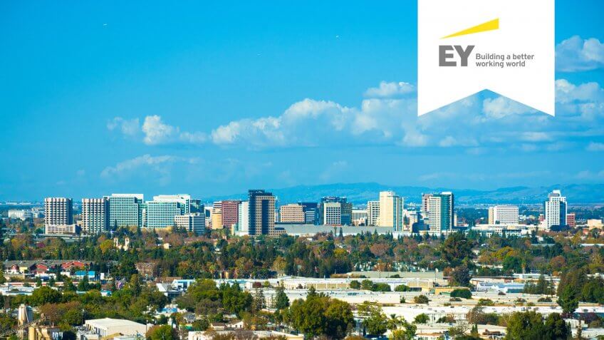 Vista of the San Jose skyline, with puffy clouds in the background and residential areas in the foreground.