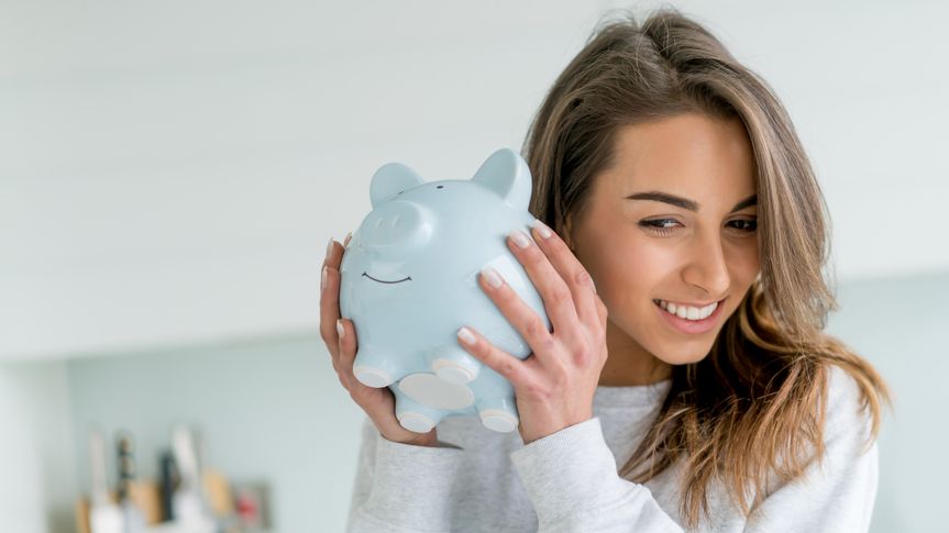 Happy young woman saving money in a piggybank - home finances concepts.