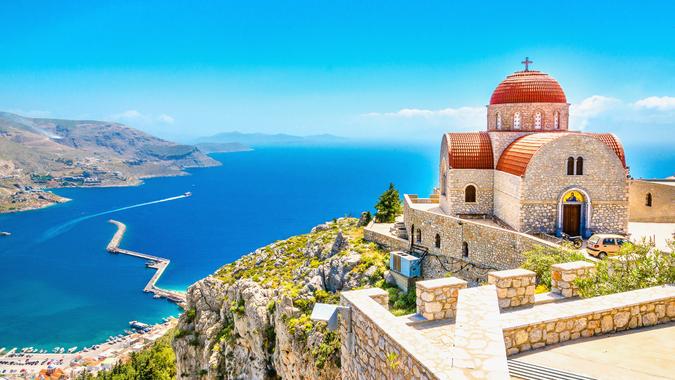 Amazing view on remote church with red roofing on the Cliff of the sea, Greece.