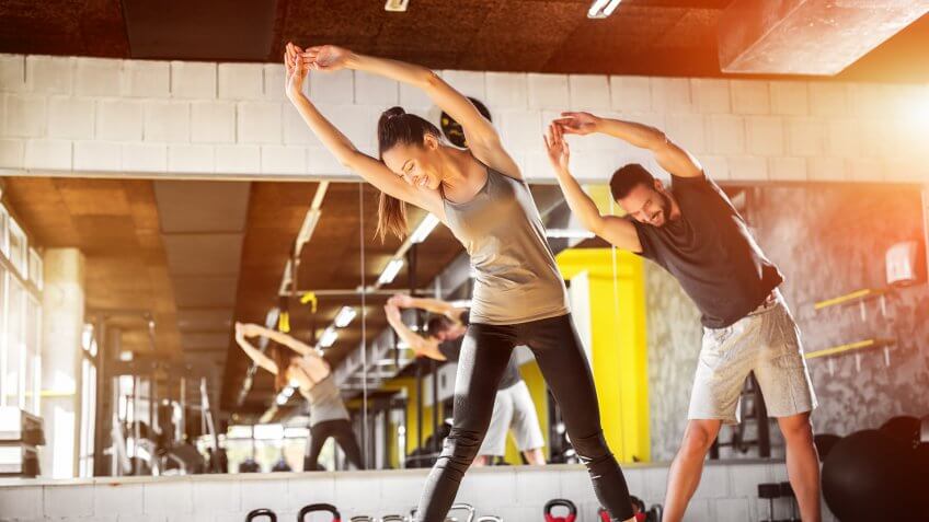 man and woman stretching, workout-gym