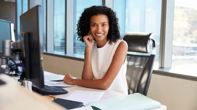 Portrait Of Businesswoman At Office Desk Using Computer.