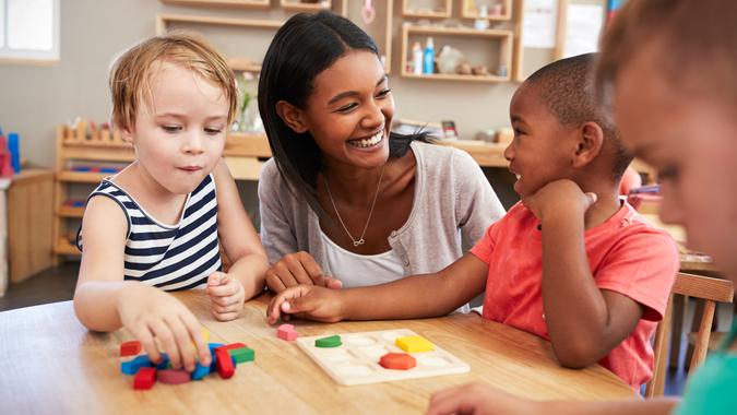 Teacher And Pupils Using Wooden Shapes In Montessori School.