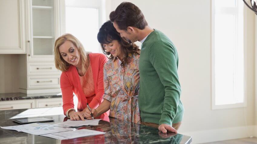 Female realtor discussing documents with couple.