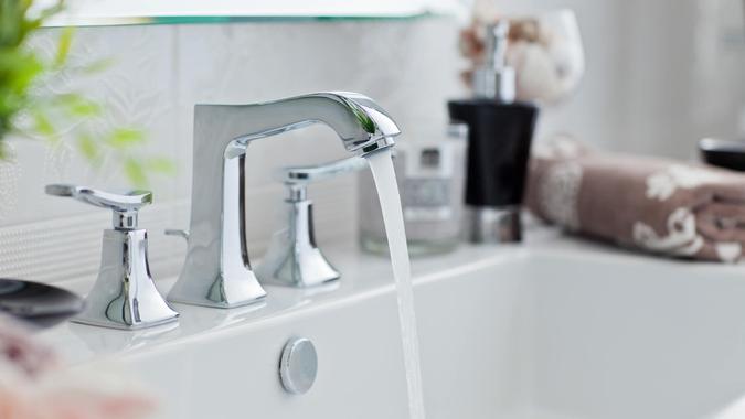 Water pouring out of modern bathroom faucet.