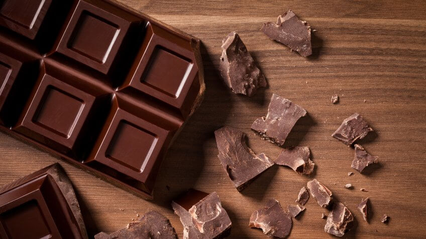 Chocolate bar and chocolate chunks shot directly above on dark wood table.