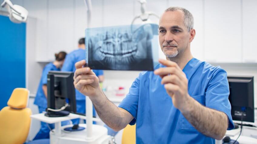 Mature male orthodontist looking at X-ray image.