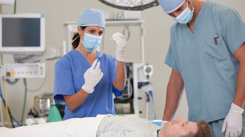 25-29 Years, 30-34 Years, 40-44 Years, Applying, Arizona, Care, Caucasian Ethnicity, Day, Doctor, Horizontal, Hospital, Indoors, Mature Women, Mid Adult Men, Patient, Phoenix, Physician, Scrubs, Surgeon, Three People, USA, Waist Up, Young Men, anesthesia, anesthesiologist, anesthetic, health, healthcare, iv drip, medical, medicine, operating room, surgery, surgical, surgical mask
