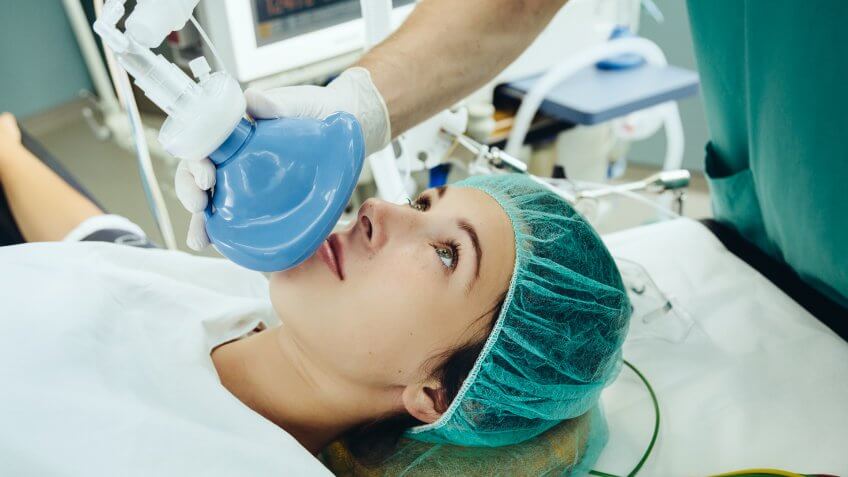Patient on operating table being given an anesthetic mask.