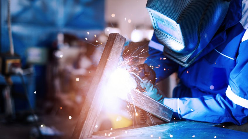 Blue collar worker or engineer working in industrial production plant, dealing with metal processing, hydraulic machinery, production lines and other pprocessing industry machines.