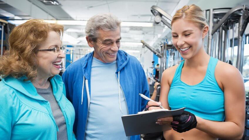 Gym trainer giving senior couple membership information.