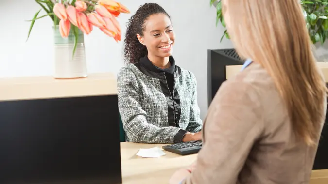 Caucasian female bank customer transacting with a bank teller at a retail bank.