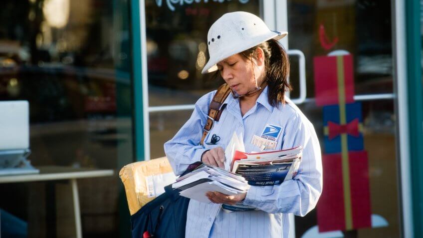 Los Angeles, Califirnia, USA - November 19, 2012: A mail carrier walks down a busy commercial and retail section of Santa Monica Blvd delivering letters and packages.