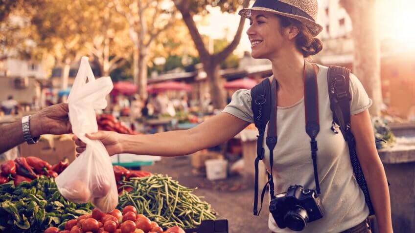Shot of a woman buying fruit and vegetables at a market in a foreign cityhttp://195.