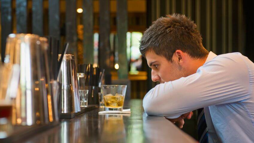 Lonely Hispanic businessman sitting at bar.