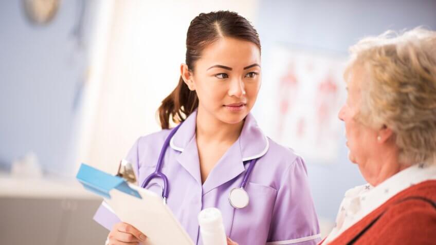 a young nurse stands and chats to a senior woman patient as she leaves the surgery.