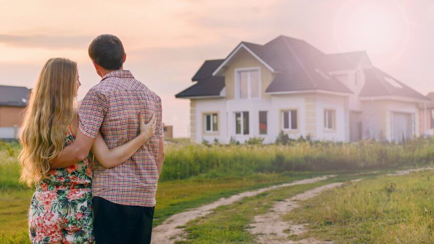 Young Couple Standing Outside Dream Home.