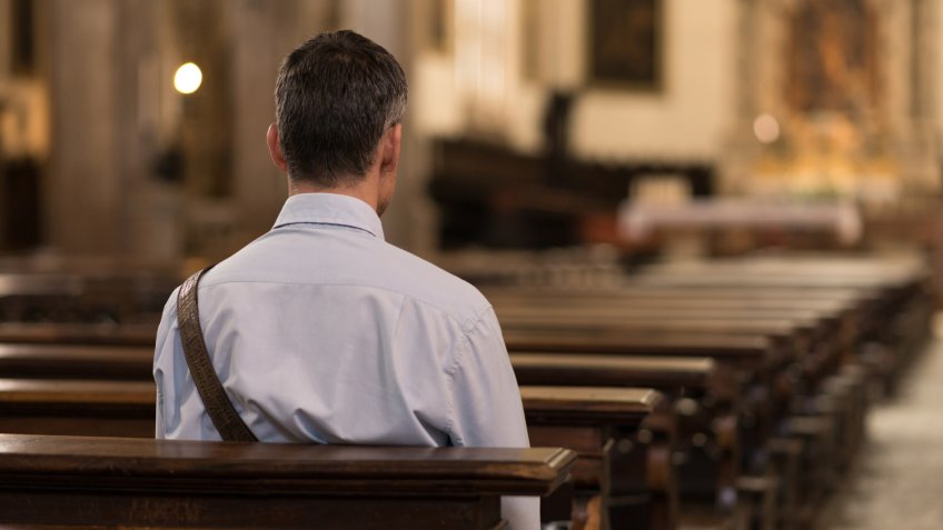 Man sitting in a pew at Church and meditating, faith and religion concept.