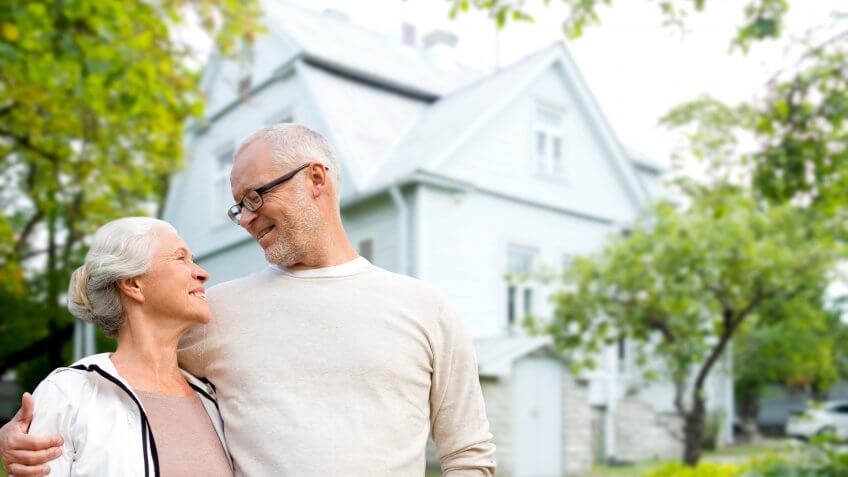 family, age, home, real estate and people concept - happy senior couple hugging over living house background.
