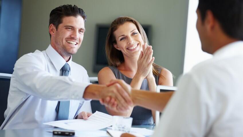Two young entrepreneurs shaking hands after receiving a tender for their business venture.