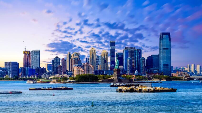 The skyline of Jersey City, New Jersey from New York Harbor with the Statue of Liberty in the foreground.