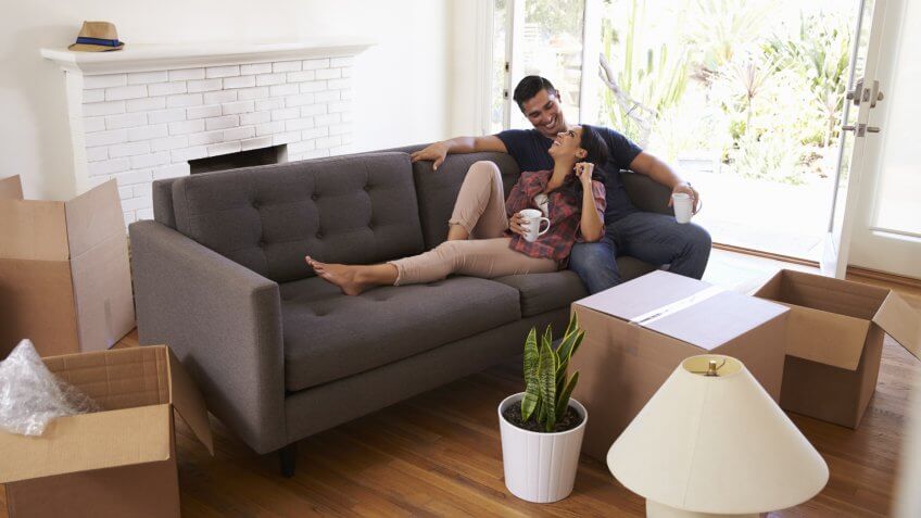 Couple On Sofa Taking A Break From Unpacking On Moving Day.