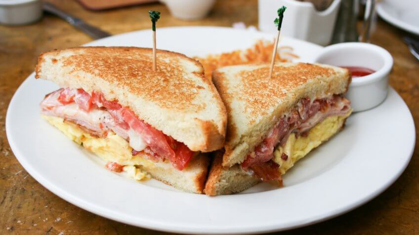 Eggs, bacon and cheese breakfast sandwich with hash brown potatoes, close up, lifestyle, horizontal.