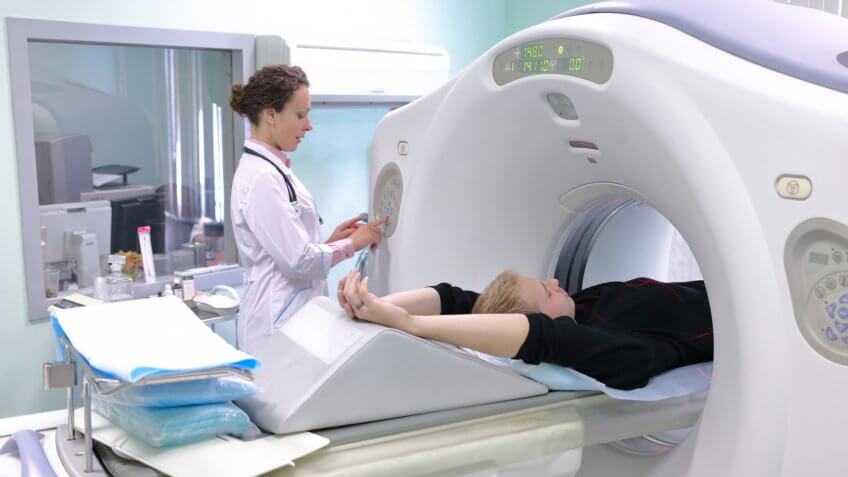 Radiologic technician show magnetic resonance exam procedure, focus on boy.