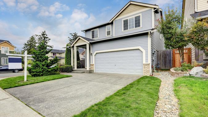 Exterior of large blue house with garage and column porch.