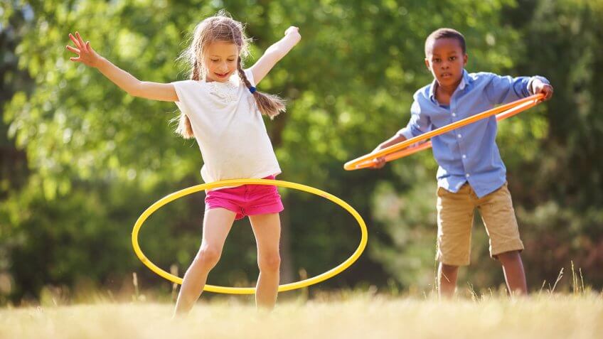 Girl and boy with hula hoop playing at the park.