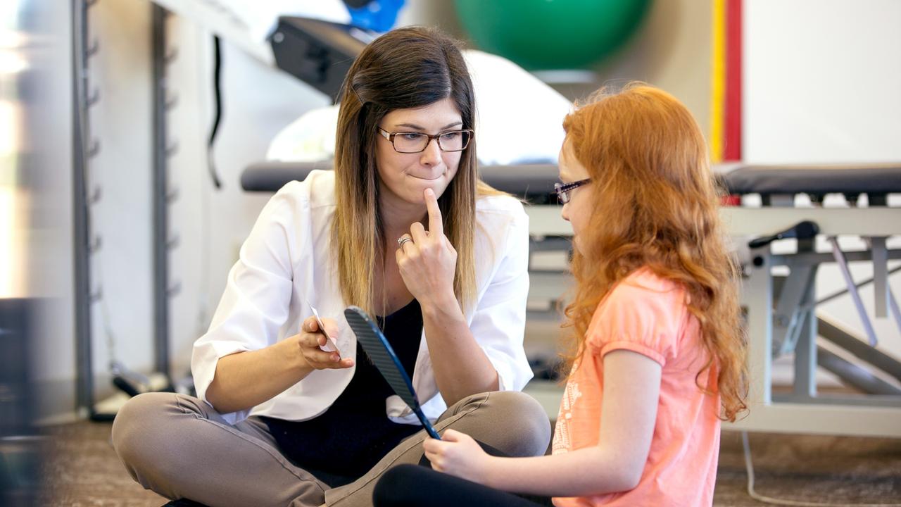 Young female speech therapist helping a young patient with her technique.