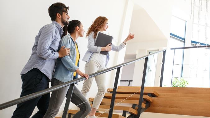 Female Real Estate agent shows interior to young couple.