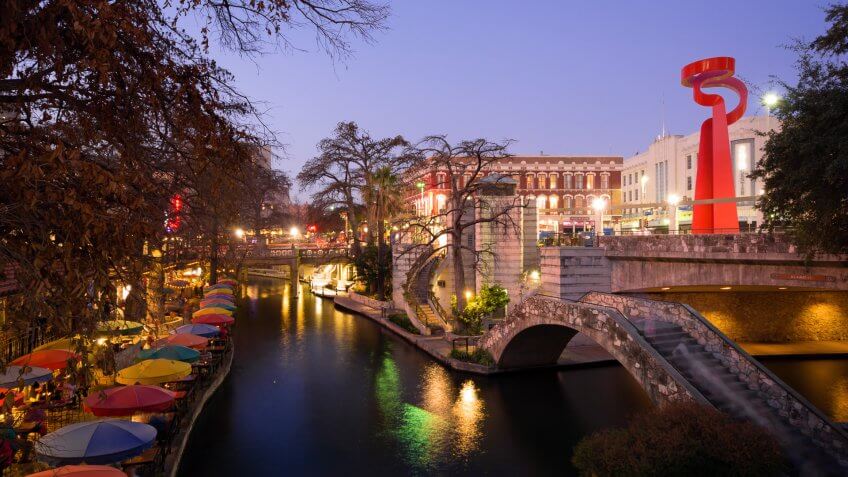 San Antonio, United States - February 18, 2014: People meander about the River Walk during the nighttime while others dine at the restaurant of Casa Rio next to the water.