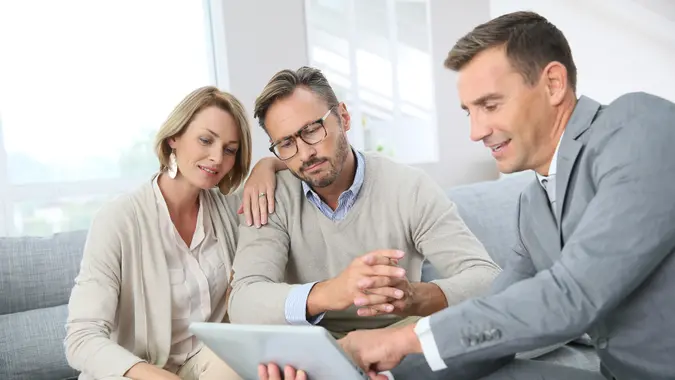 A couple sitting with an insurance sales agent, looking over documents.