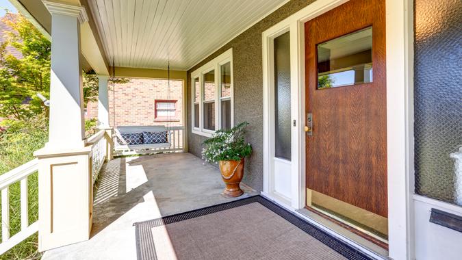 Front covered porch with hanging swing and flower pot.
