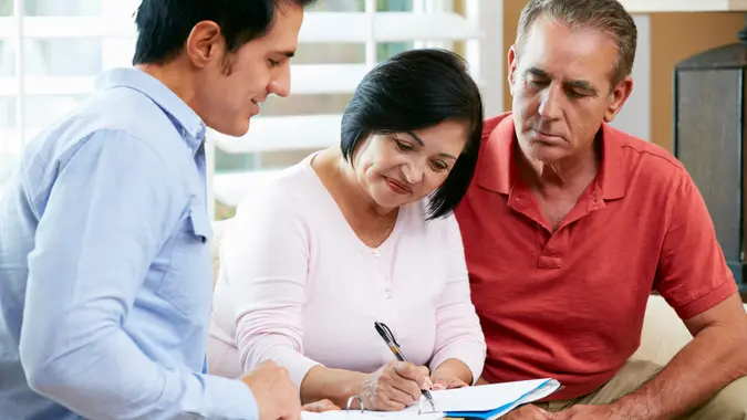Financial Advisor Talking To Senior Couple At Home.