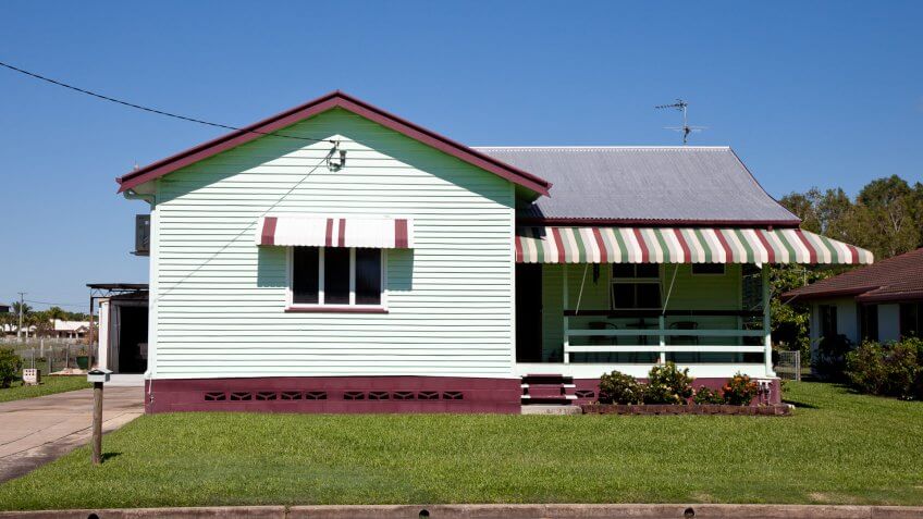 Tidy little old style house with clear blue sky and green grass and overhead power line connected to it – Queensland Australia.