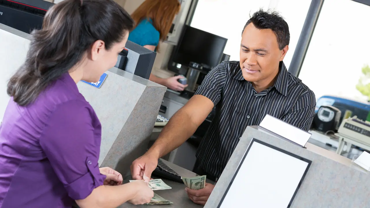 Customer at the bank getting money from the teller.