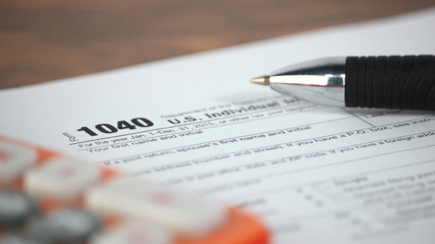 US tax form with pen and calculator selective focus / taxation concept.