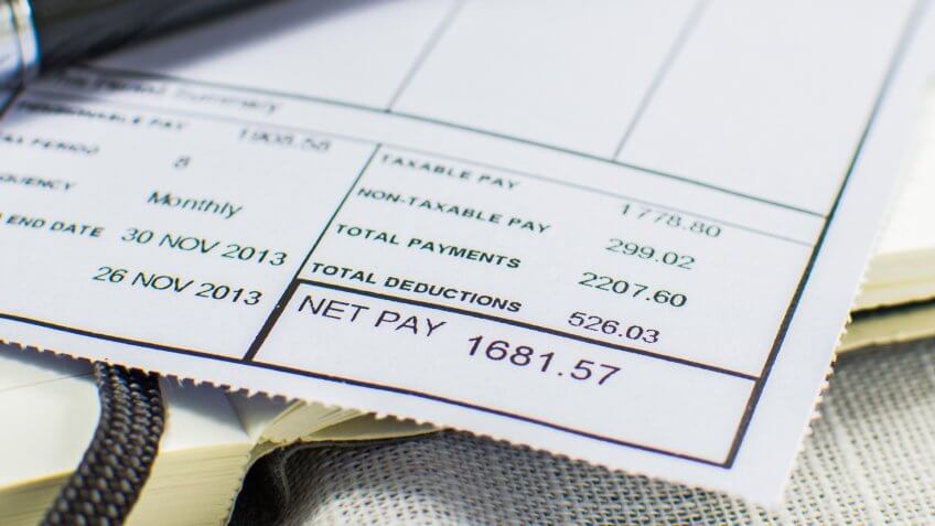 Wage slip on pad with black pen.