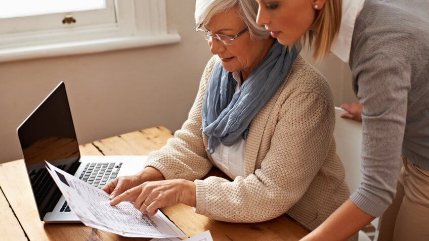 Cropped view of a senior woman receiving help with her finances from her granddaughter.