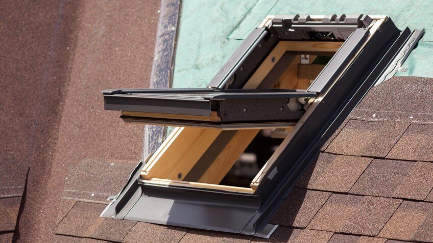 Open skylight on a roof shingles under construction.