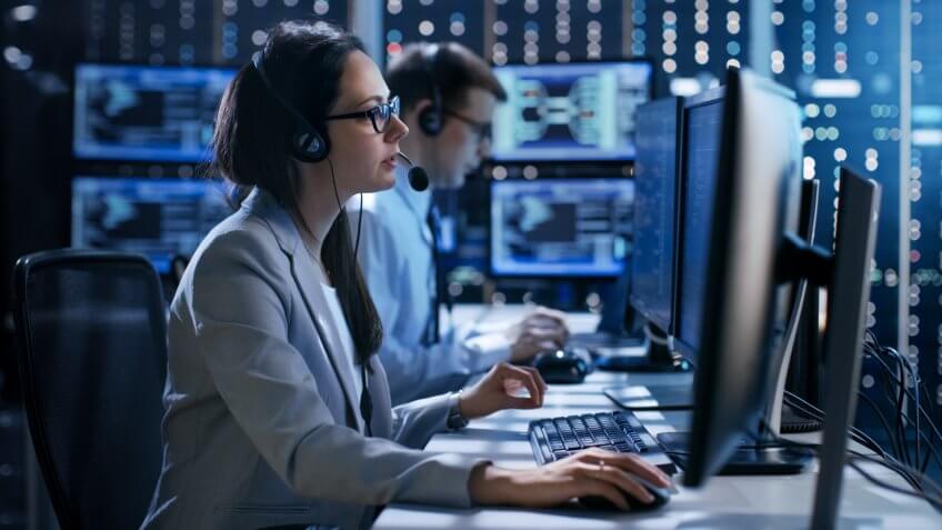Female working in a Technical Support Team Gives Instructions with the Help of the Headsets.