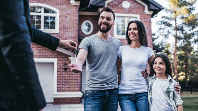 Happy family is taking keys from their new house from broker and smiling.