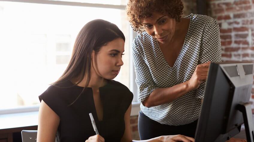Two Businesswomen Working On Computer In Office.