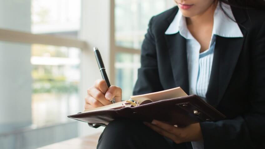 business woman taking notes in a planner with a pen