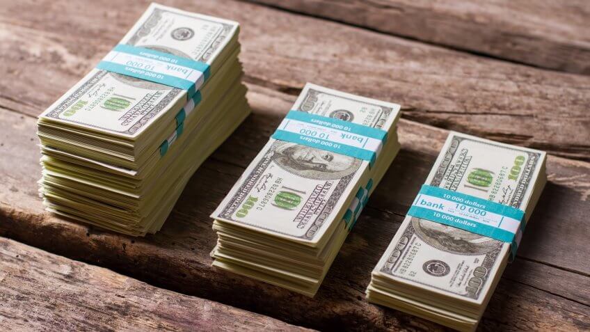 Dollar bundles on wooden background.