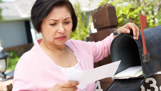 Worried Senior Hispanic Woman Checking Mailbox.