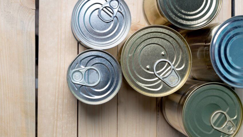 Tin cans for food on wooden background.