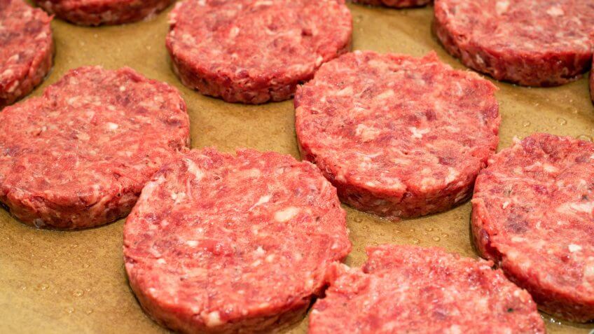 Fresh raw beef burger patties on paper background.