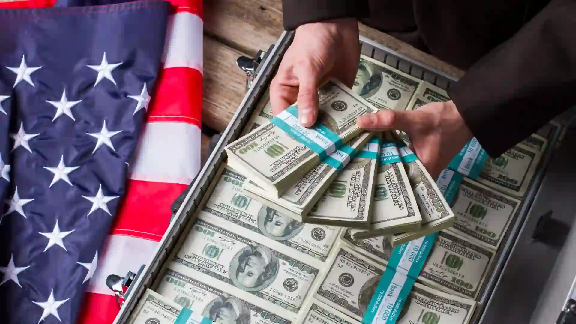 Male hands holding dollar bundles.